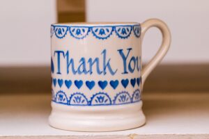 Emma Bridgewater NHS 75 cup. The white cup is decorated with blue paint and says 'Thank you'.