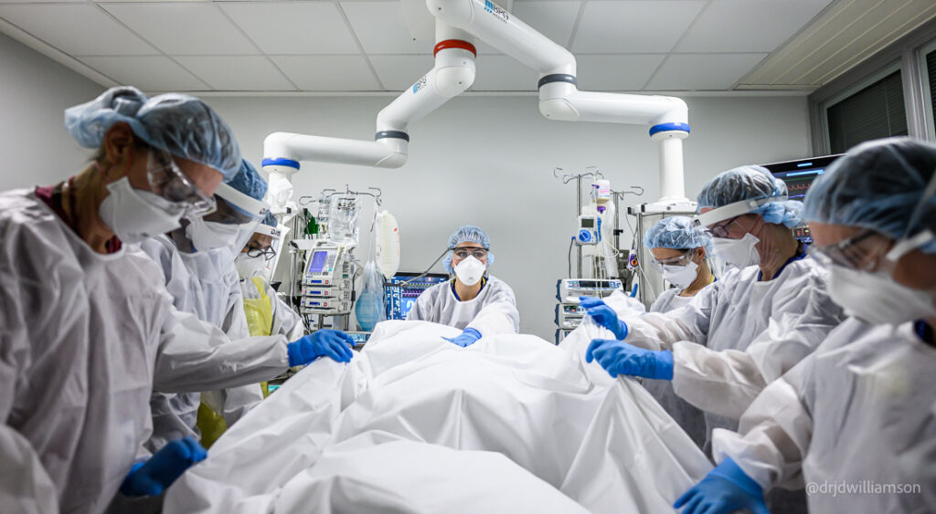 Surgeons, doctors and nurses around a patient in a theatre room