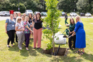 Group of people standing around a newly planted tree