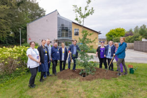 Group of people from great Oaks standing around a newly planted tree