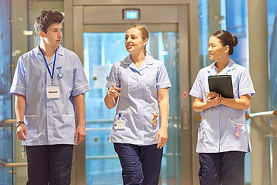 Three healthcare professionals walking down a hospital corridor.
