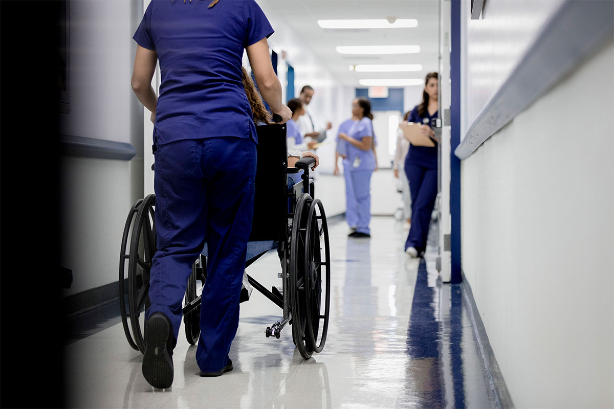 Wheelchair being pushed down a hospital corridor